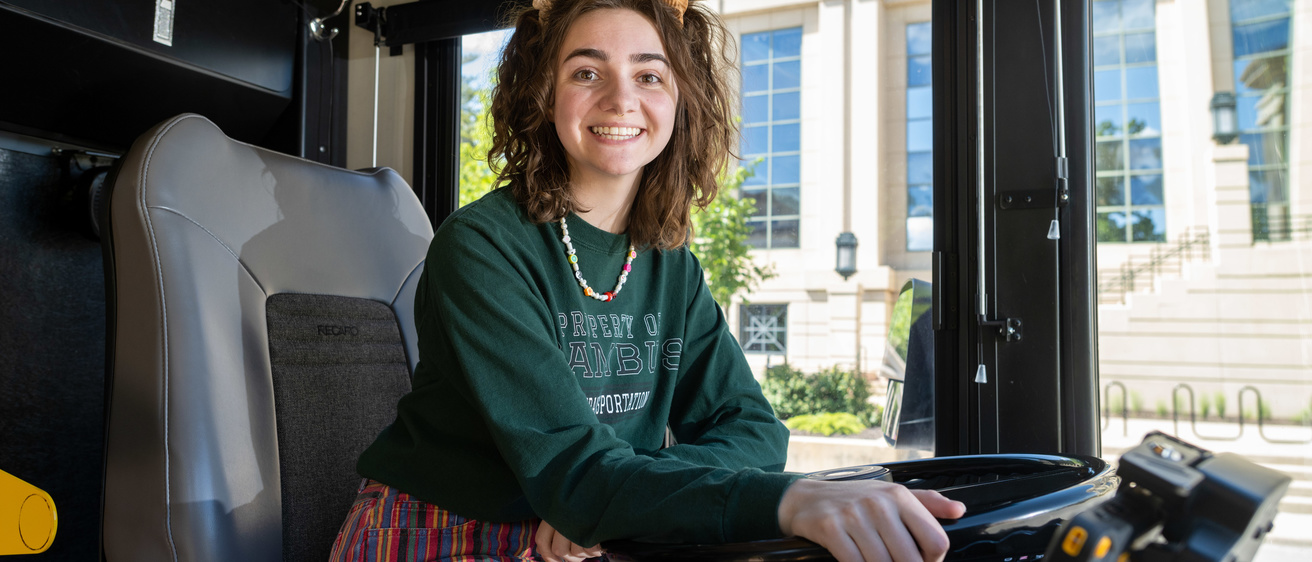 student poses in CAMBUS driver's seat